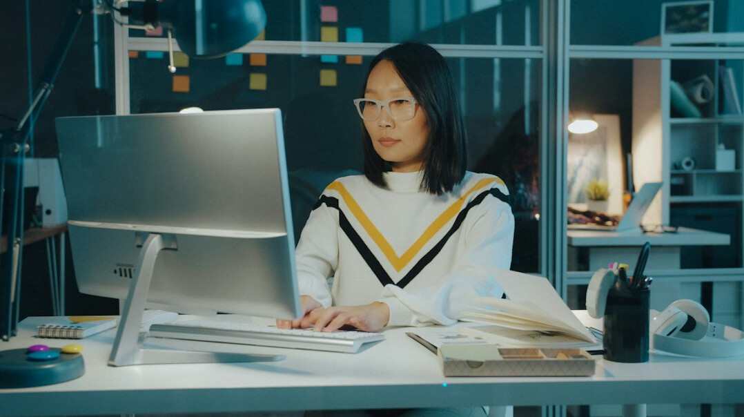 Young South Asian woman video editor working at a multi-monitor desk